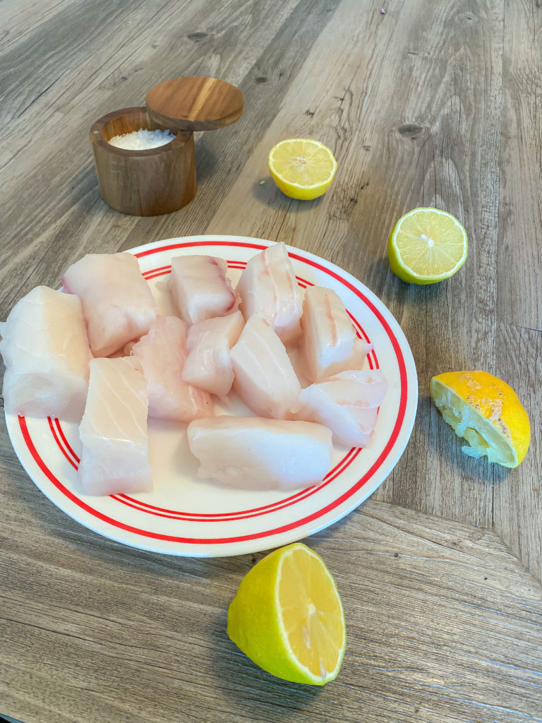 Raw Halibut cut into chunks on plate with lemon around it to make Poor Man's Lobster